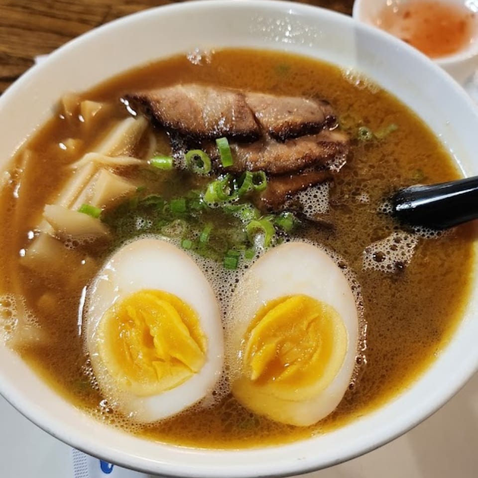 A bowl of Fuji Japanese Cuisine ramen with pork, bamboo shoots, green onions, and two soft-boiled eggs.