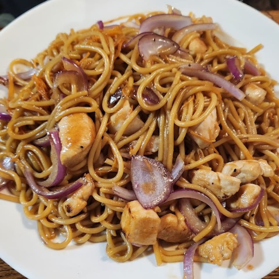 Close-up of Fuji Japanese Cuisine's chicken yakisoba with noodles, chicken, and red onions.
