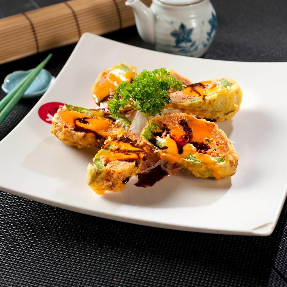 Fuji Japanese Cuisine's fried sushi rolls with orange sauce and dark drizzle, garnished with parsley.