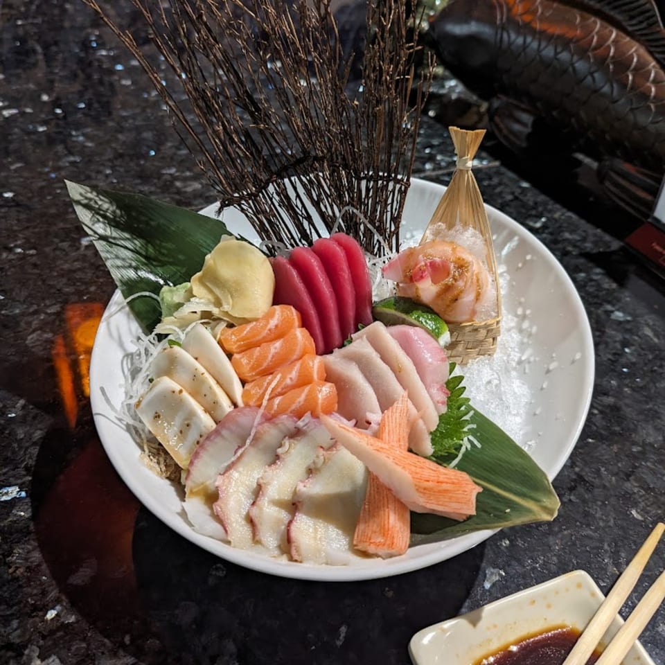 A large platter of colorful sashimi, including tuna, salmon, and octopus, on a bed of ice.